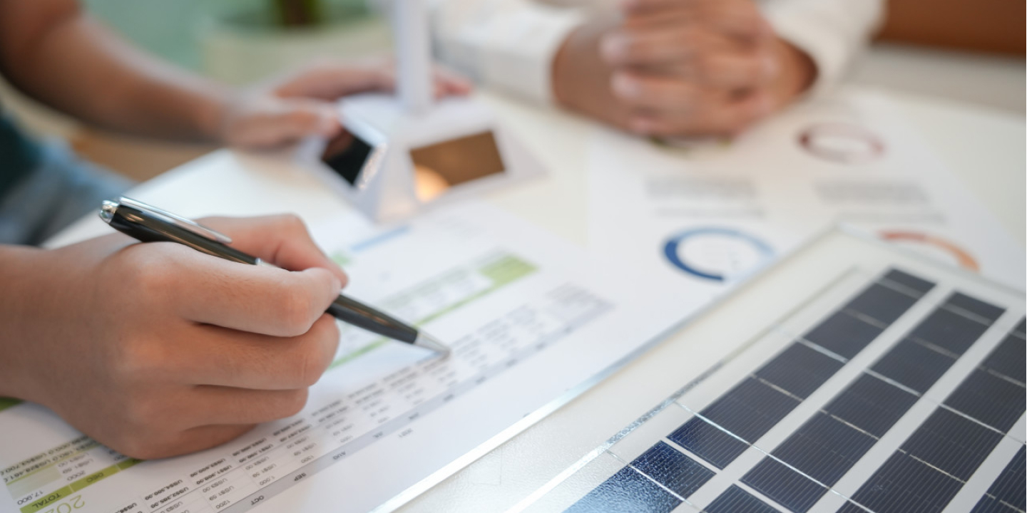 Close-up of Solavita EPC team analyzing solar project financial data with solar cell sample on desk