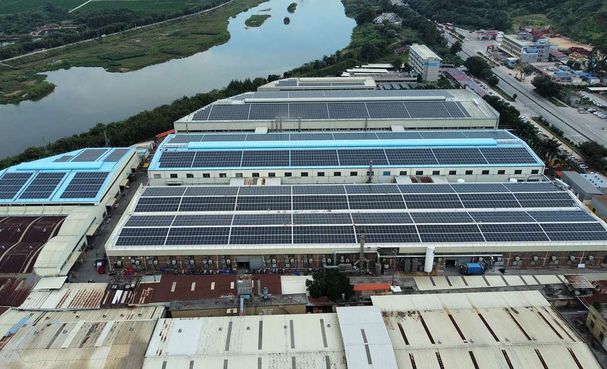 A large-scale commercial rooftop solar installation on industrial buildings, demonstrating sustainable energy integration into factory operations.