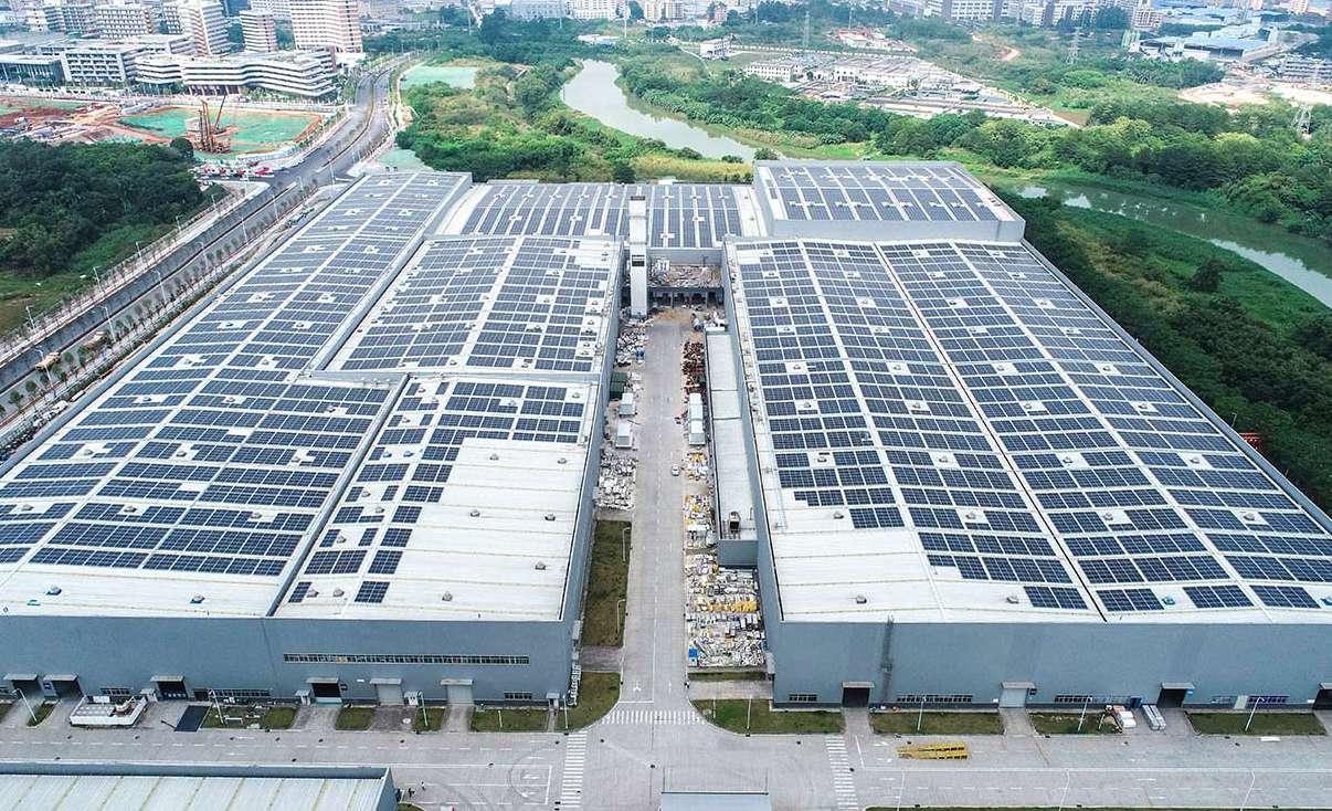 A large industrial rooftop solar installation across multiple factory buildings, exemplifying scalable green energy deployment in urban industrial zones