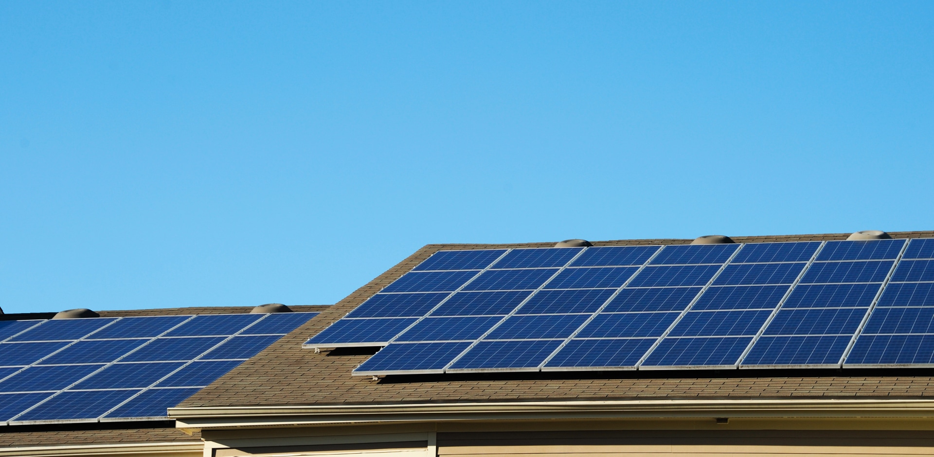 Solavita Residential rooftop with evenly aligned solar panels under a clear blue sky.