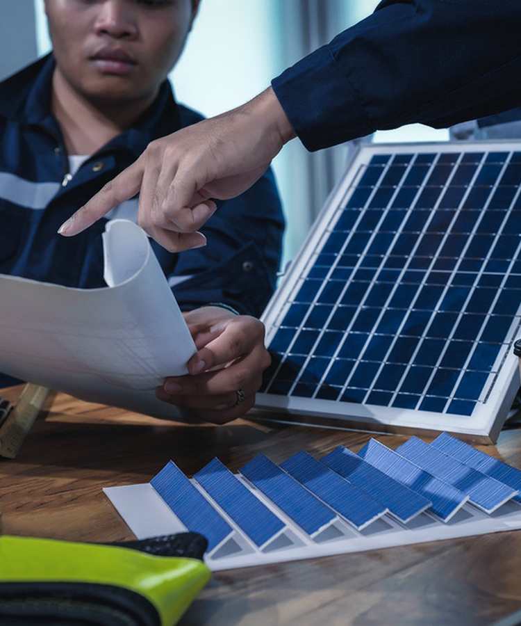 Engineers discussing solar system design with Solavita panel samples and blueprint on table